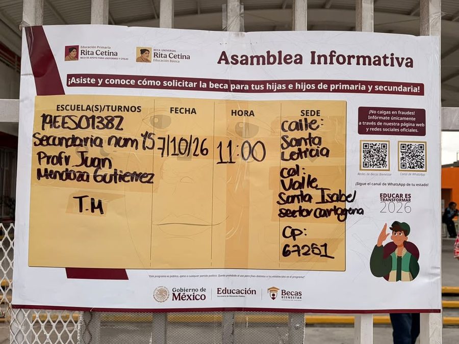 Cartel de la Asamblea Informativa de Becas colocado en el acceso del plantel, con los datos de la escuela escritos a mano.